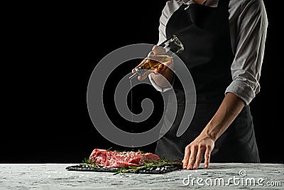 Preparation of the chef by steak cook.Preparation of fresh beef or pork. Horizontal photo with dark black background. Stock Photo