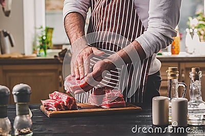 Preparation of dinner. Cooking, processing of meat beef, tenderloin . Person man`s hands marinates meat - sprinkles with Stock Photo