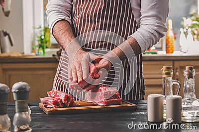 Preparation of dinner. Cooking, processing of meat beef, tenderloin . Person man`s hands marinates meat - sprinkles with Stock Photo