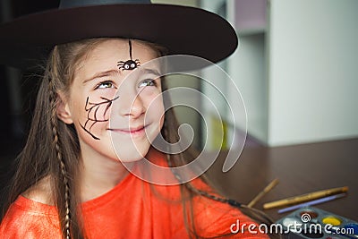 Preparation for Halloween. child in a witch outfit doing face painting. cute spider. idea of simple suit, diy Stock Photo