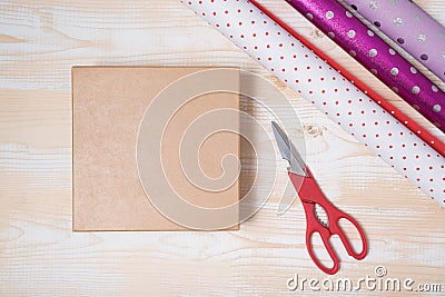 Preparation for the holiday. Gift wrapping. Cardboard box, wrapping paper and scissors on a wooden background. Top view Stock Photo