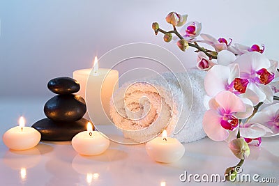 Preparation for massage in white with towels, stones, candles and orchid Stock Photo