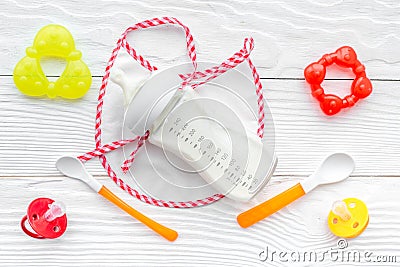 Preparation of mixture baby feeding with infant formula powdered milk in bottle with bib on white background top view Stock Photo