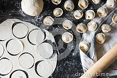 Preparation of pelmeni. Top view. Ingredients on black table. Traditional Russian cuisine. Stock Photo