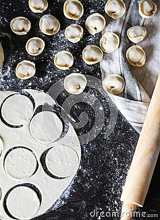 Preparation of pelmeni. Top view. Ingredients on black table. Traditional Russian cuisine. Stock Photo