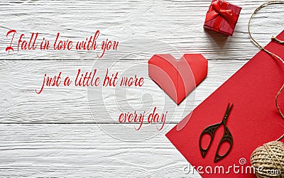 Preparation for Valentine`s Day. Red sheet of paper, scissors, red origami heart, skein of twine and gift box on a white textured Stock Photo