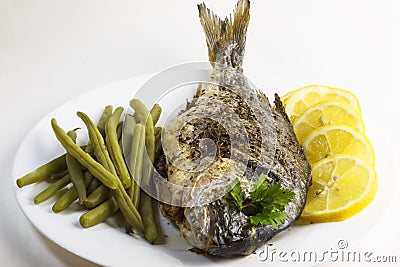 Prepared, cooked, fried, baked dorado fish or sea bream with green beans and lemon slices Stock Photo