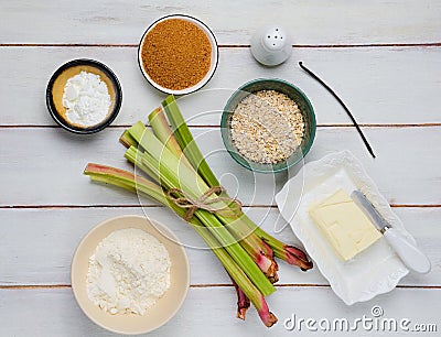 Prepared ingredients for cooking rhubarb crumble on a light wooden background. Rhubarb recipes Stock Photo
