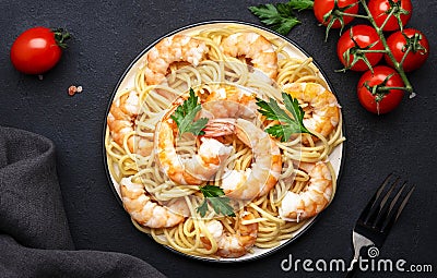 Prepared spaghetti pasta with shrimp, olive oil and parsley in plate on black table background. Top view Stock Photo