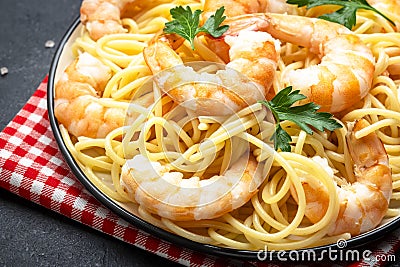 Prepared spaghetti pasta with shrimp, olive oil and parsley in plate on black table background. Top view Stock Photo
