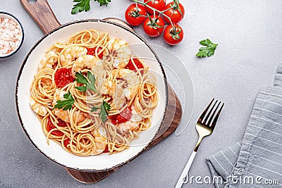 Prepared spaghetti pasta with shrimp, red tomatoes, olive oil and parsley on gray background. Top view, copy space Stock Photo