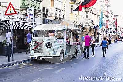 Preparing for evening fair for Halloween, food truck decorated with pumpkin and candid people Editorial Stock Photo