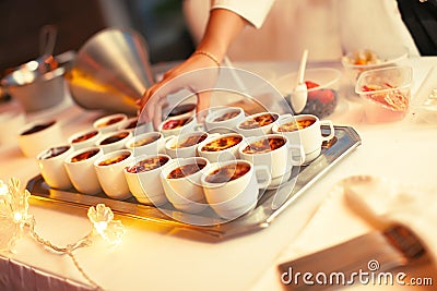 Preparing for a festive banquet. Serving the buffet table with dessert cakes. Female hands are laying out dessert spoons. Stock Photo