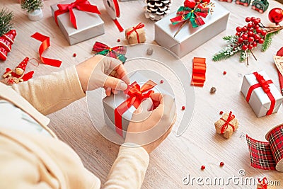 Preparing gifts for Christmas and New Year. The girl prepares a gift by tying a bow Stock Photo