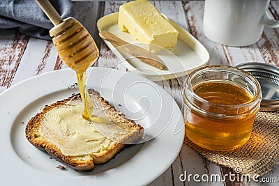 Preparing a healthy breakfast with a toast with butter and pure organic honey from bees Stock Photo