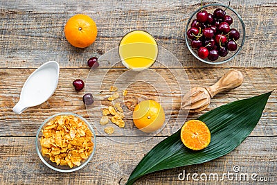 Preparing healthy summer breakfast. Muesli, milk, oranges, cherry, on wooden table background top view Stock Photo