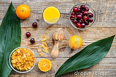 Preparing healthy summer breakfast. Muesli, oranges, cherry, juice on wooden table background top view Stock Photo