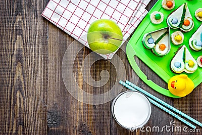Preparing quick lunch for schoolchild. Funny sandwiches, milk, fruits on dark wooden table background top view copyspace Stock Photo