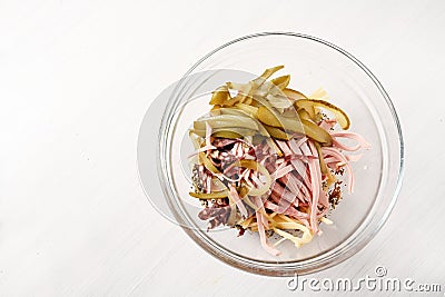 Preparing sausage salad german wurstsalat in a glass bowl with onion, cheese and pickled gherkins, light background with copy Stock Photo