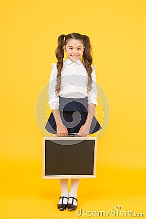 Preparing small child for school. Small girl holding black-board on yellow background. Small kid with empty chalkboard Stock Photo