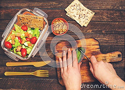 Preparing takeaway meal for children. School lunch box with salad, salmon, avocado and nuts on rustic wooden background. Healthy Stock Photo