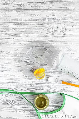 Preparing to feed baby. Puree, spoon, nipple, bottle and bib on light wooden table background top view copyspace Stock Photo