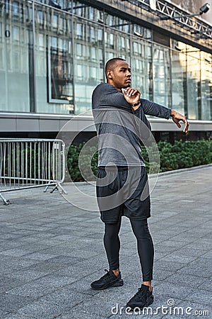 Preparing for workout. Full length portrait of african athlete stretching his arms during morning workout Stock Photo