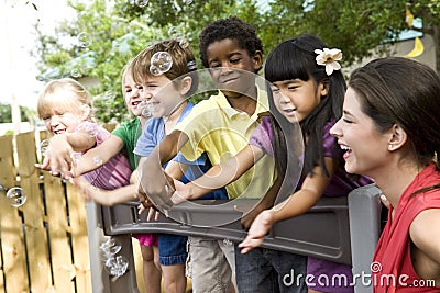 Preschool children on playground with teacher Stock Photo