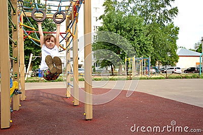 Preschool girl is engaged on the rings on the playground. sports lifestyle concept. walk in the fresh air. children play on the Stock Photo