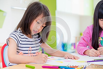 Preschool girl kid drawing with color pencil on white paper on t Stock Photo