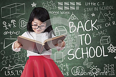 Preschool girl reads book seriously Stock Photo