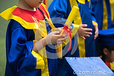 Preschool kid wearing graduation dress and holding diploma closeup Editorial Stock Photo