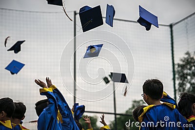 Preschool kids wearing graduated dress throwing cap and diplomat in sky in graduated celebration day. Editorial Stock Photo