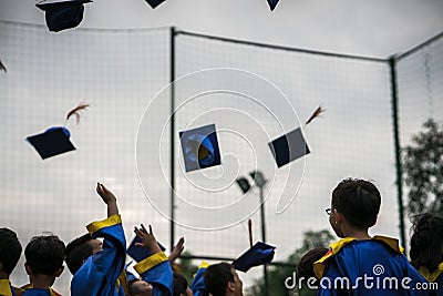 Preschool kids wearing graduated dress throwing cap and diplomat in sky in graduated celebration day. Editorial Stock Photo