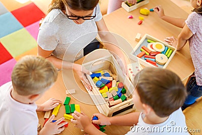 Preschool teacher with children playing with colorful didactic toys at kindergarten Stock Photo