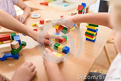 Preschool teacher with children playing with colorful wooden didactic toys at kindergarten Stock Photo