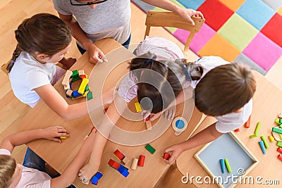 Preschool teacher with children playing with colorful wooden didactic toys at kindergarten Stock Photo