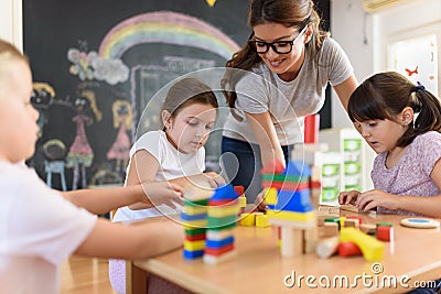 Preschool teacher with children playing with colorful wooden didactic toys at kindergarten Stock Photo