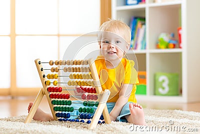 Preschooler baby learns to count. Cute child playing with abacus toy. Little boy having fun indoors at kindergarten Stock Photo