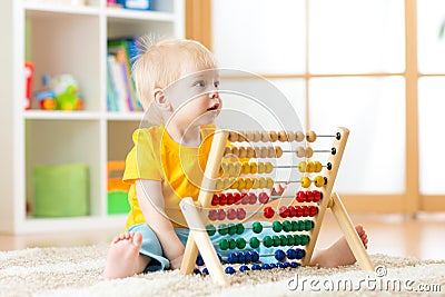 Preschooler baby learns to count. Cute child playing with abacus toy. Little boy having fun indoors at kindergarten Stock Photo