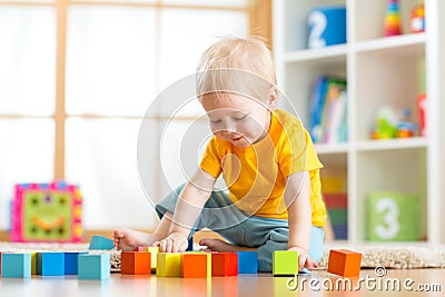 Preschooler child playing with colorful toy blocks. Kid playing with educational wooden toys at kindergarten or day care center. Stock Photo