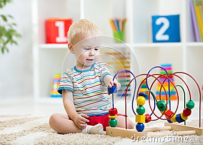 Preschooler child playing with developmental toy. Kid plays with toy beads at kindergarten or daycare center. Toddler Stock Photo