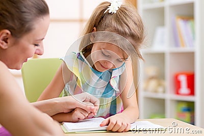 Preschooler Child Reading with Mother In Nursery Stock Photo