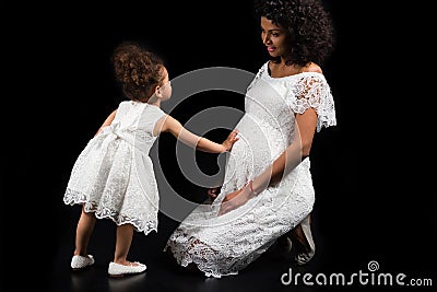 Daughter touching pregnant mothers belly Stock Photo