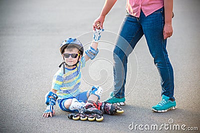 Preschooler falls over while rollerblading with mother in the park Stock Photo