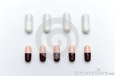 Prescription drugs, capsules of different colors between white capsules and dark reddish brown and soft pink all mix in . Stock Photo