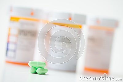 Green capsules in front of orange pharmacy bottles Stock Photo