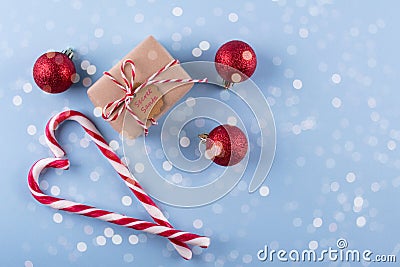 Present from secret Santa. Wrapped gift box with notes, christmas toys , candy cane on blue pastel background. Stock Photo