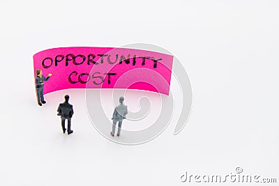 Presentation meeting with miniature figurines posed as business people standing in front of post-it note with Opportunity Cost Stock Photo