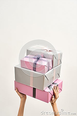 Presents for Womens day. Female hands holding gift pile over the head against light background Stock Photo